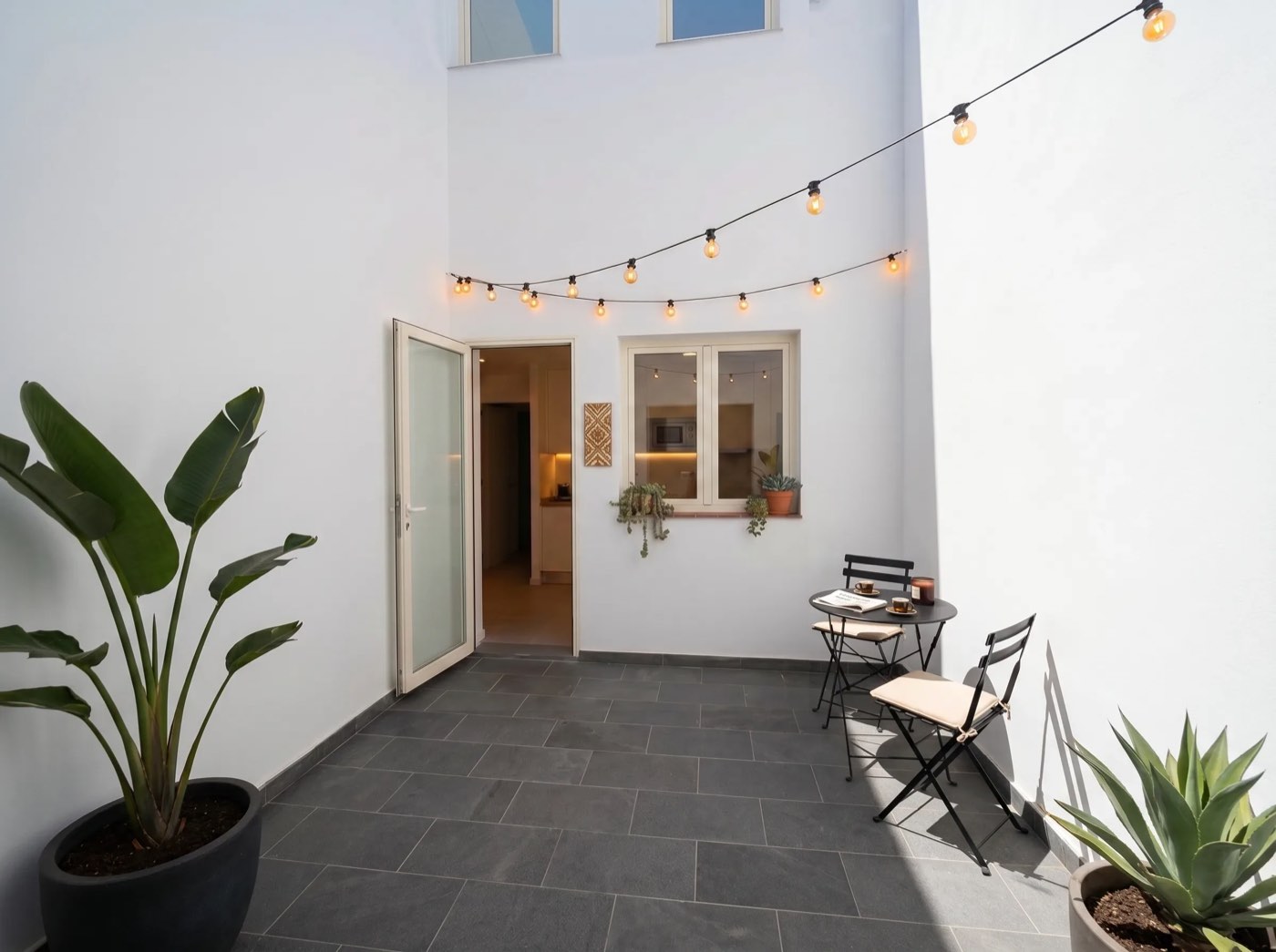 Patio privado del Dúplex 01 con guirnaldas de luces y mesa de bistró